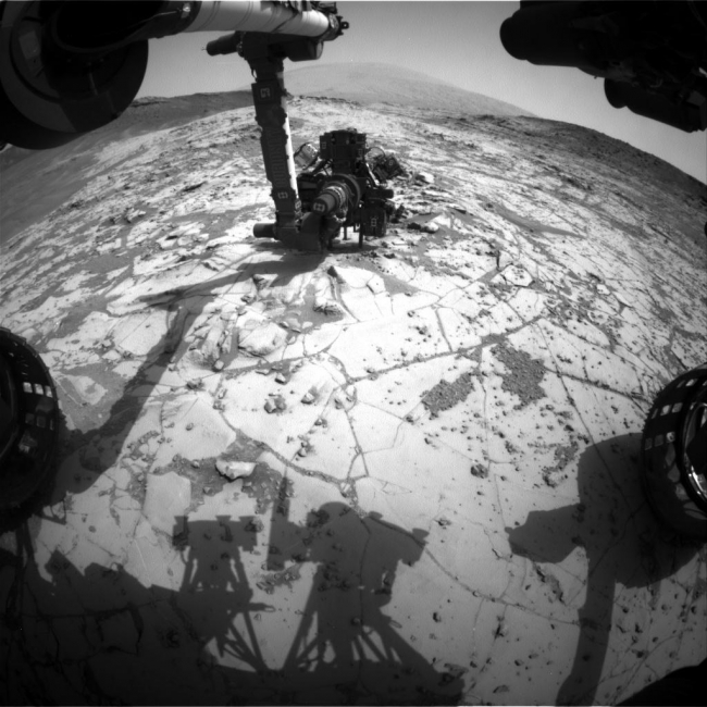 Curiosity Conducting Mini-Drill Test at 'Mojave', This view from the wide-angle Hazard Avoidance Camera (Hazcam) on the front of NASA's Curiosity Mars Rover shows the rover's drill in position for a mini-dri...