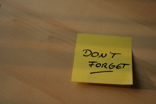 A POST-IT saying "Don't forget!" sticked to a table top, 