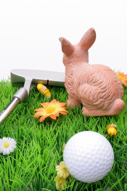 Golfer's easter bunny, A strip of artificial grass with a white golf ball in front and an easter bunny and a putter in the background in front of a white backdrop. Vertical. Great ...