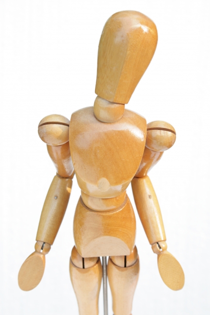 Innocent mannequin, A wooden painter's posing mannequin looking up into the camera, gesturing innocence. White backdrop, plenty of fill-light, top-down view. Vertical.