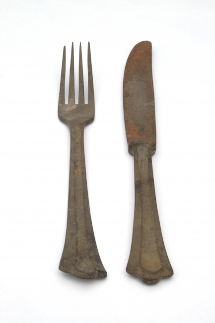 Rusty fork and knife, A well aged rusty pair of fork and knife, laid parallel as in a place setting. Brown, red and dirt marks, aged metal against a white background. Vertical. Cr...