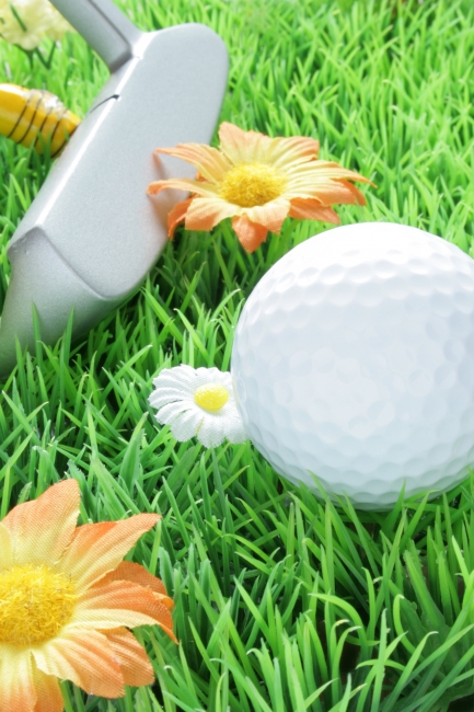 Goldball and putter on artificial grass, great depth of field, Goldball and putter on artificial grass with white and orange flowers, great depth of field, crisp focus all over