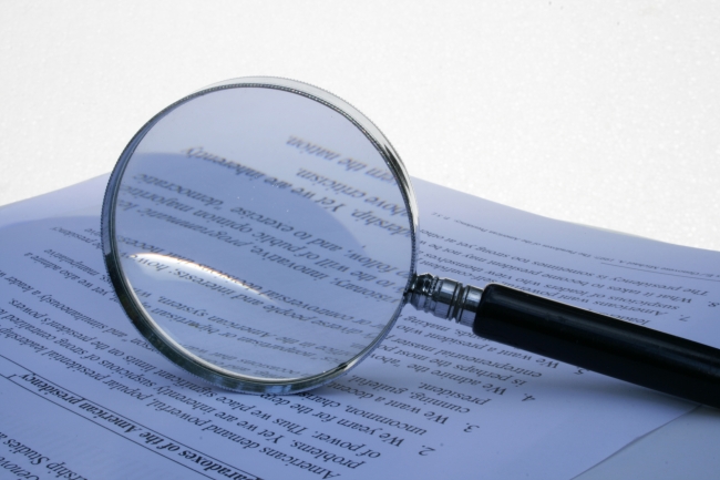 A magnifier on a piece of legal paper, against white, 