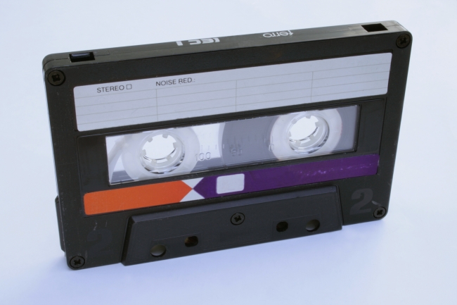 80s audio cassette, upright, An 1980s style tape audio cassette as it was sold in asian markets. Used condition with marks and scratches. In upright position on white background