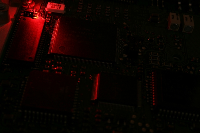 Circuit board with red light, A circuit board in close-up, lit by a red LED light source from upper left side, revealing CPUs, integrated-circuits (IC)  chips and various electronic compo...