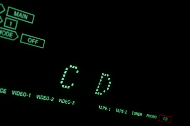 Green Hi-Fi LCD display in close-up CD, A hi-fi receiver's green dot-matrix LCD display in extreme close-up showing CD (compact disc). Tilted view with green font on black background.