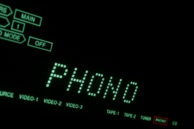 Green Hi-Fi LCD display in close-up PHONO, A hi-fi receiver's green dot-matrix LCD display in extreme close-up showing Phono (record player). Tilted view with green font on black background.