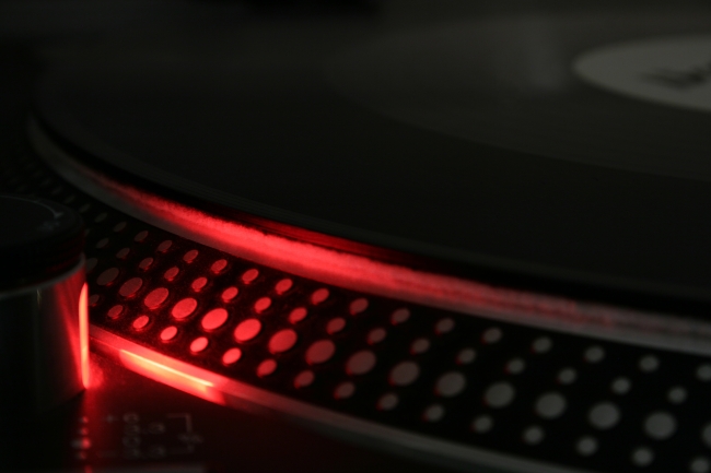 Turntable rim close-up at the speed control, Close-up of the speed control section, the left platter rim on a Technics SL-1210MK2 DJ turntable, illuminated by the red light of the strobe.