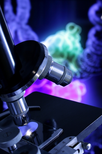 Microscope against DNA repair rendering, A black and silver microscope against a screen showing the repair process of a DNA sequence
