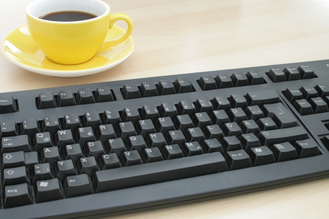 Cup of coffee on a table next to a black Cherry keyboard (different lighting), 