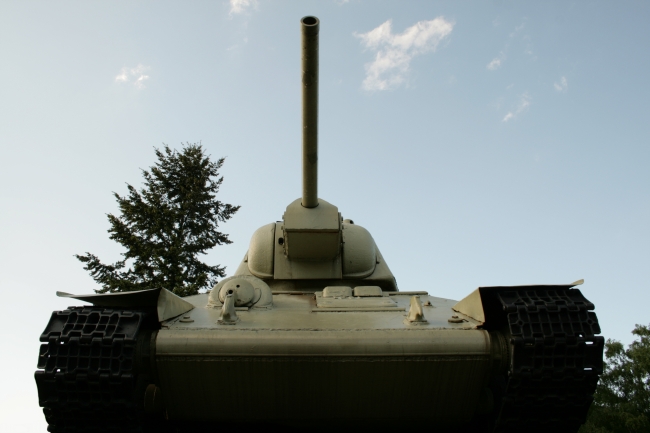 T-34 tank from low angle, Near the German Reichstag in Berlin as part of the Sowjetisches Ehrenmal, a T-34 tank, frontal from a low angle against sky and cedars