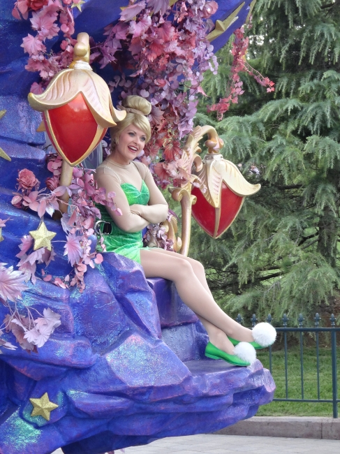 Tinkerbell, sitting on a "backseat" of one of the carriages during the Big Parade on Parade Route in Central Plaza